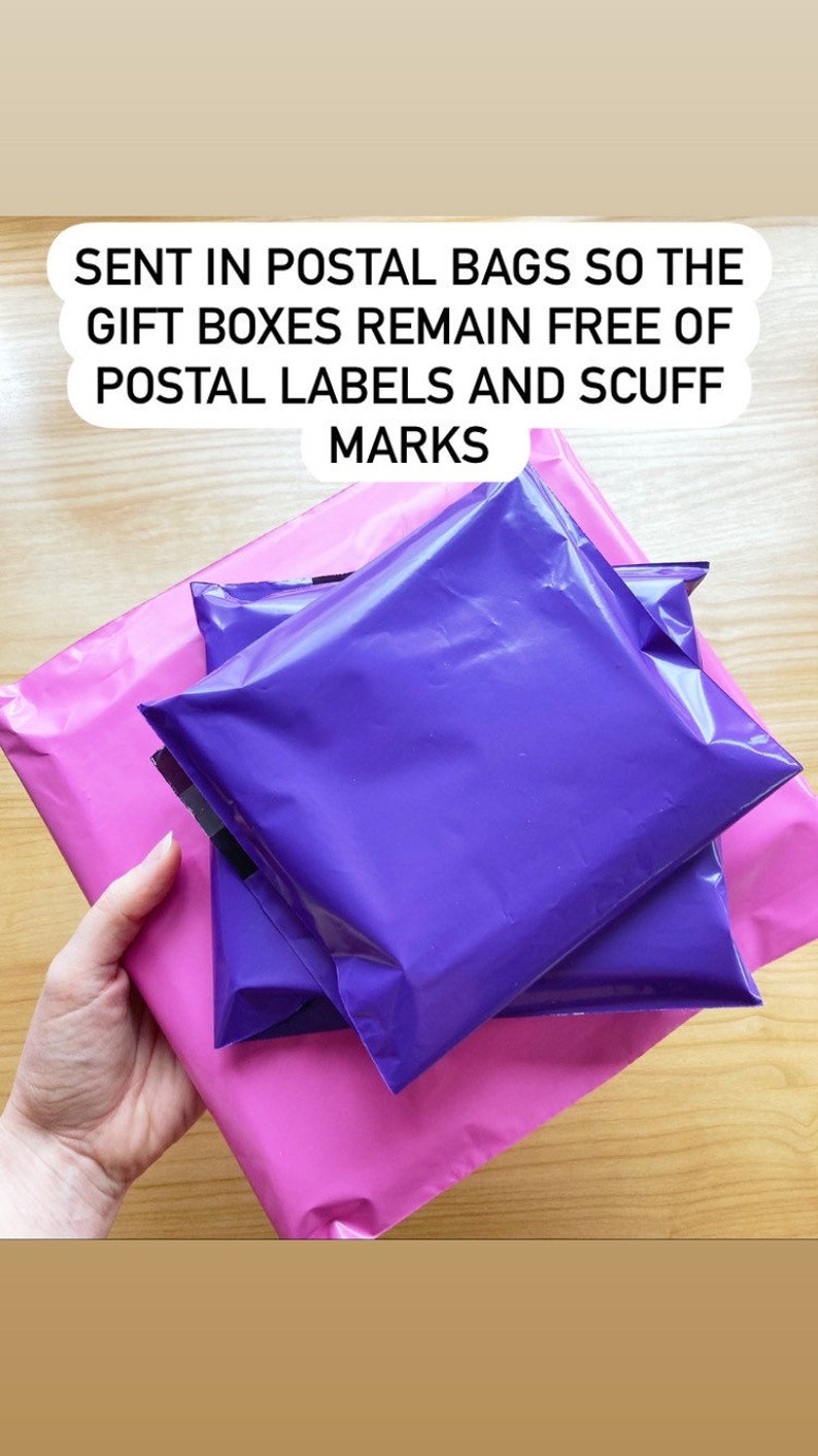 May include: Three purple mailing envelopes are stacked on top of a pink mailing envelope. The text on the top of the image reads "SENT IN POSTAL BAGS SO THE GIFT BOXES REMAIN FREE OF POSTAL LABELS AND SCUFF MARKS."