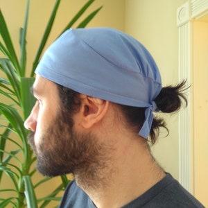 May include: A light blue surgical scrub cap with a tie at the back. The cap is made of a soft, comfortable fabric and is designed to keep hair out of the way.