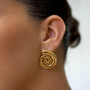 May include: Gold spiral earrings. The earrings are a simple design with a single spiral shape.