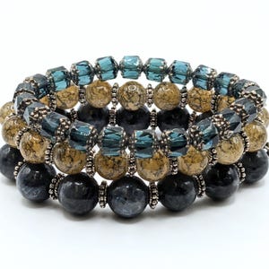 May include: Stacked bracelets featuring a mix of beads in shades of teal, brown, and black. The bracelets include faceted teal crystal beads, speckled brown beads, and smooth black beads, all strung together with silver-toned spacers.