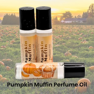 May include: Three clear glass rollerball bottles with black caps containing Pumpkin Muffin perfume oil. The labels feature an illustration of a pumpkin and a muffin with text reading Pumpkin Muffin Perfume Oil and rubykeen.com.