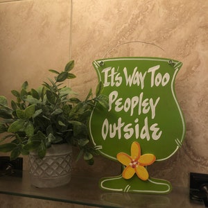 May include: Green wooden sign shaped like a margarita glass with the text "It's Way Too Peopley Outside". The sign has a yellow flower on the bottom.
