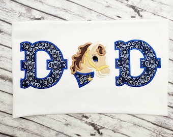 May include: A white t-shirt with the word "DAD" embroidered in blue with a paisley pattern. The letter "A" is replaced with a cartoon horse head with a blue paisley bandana.