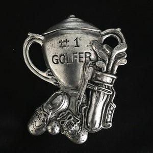 May include: A silver trophy with the words "#1 GOLFER" engraved on the side. The trophy is decorated with a golf bag and golf clubs.