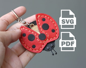 May include: A red and black ladybug keychain with a silver keyring. The ladybug has black spots and yellow stitching. The image also includes SVG and PDF file icons.