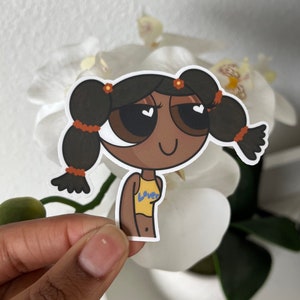 May include: A cartoon sticker of a girl with brown hair in pigtails, wearing a yellow tank top with the word "Love" on it. She has big brown eyes with white hearts in them and a big smile.