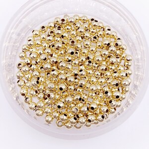 K&ouml;nnte beinhalten: Eine Schale gef&uuml;llt mit goldfarbenen Metallperlen. Die Perlen sind rund und haben eine glatte, gl&auml;nzende Oberfl&auml;che.