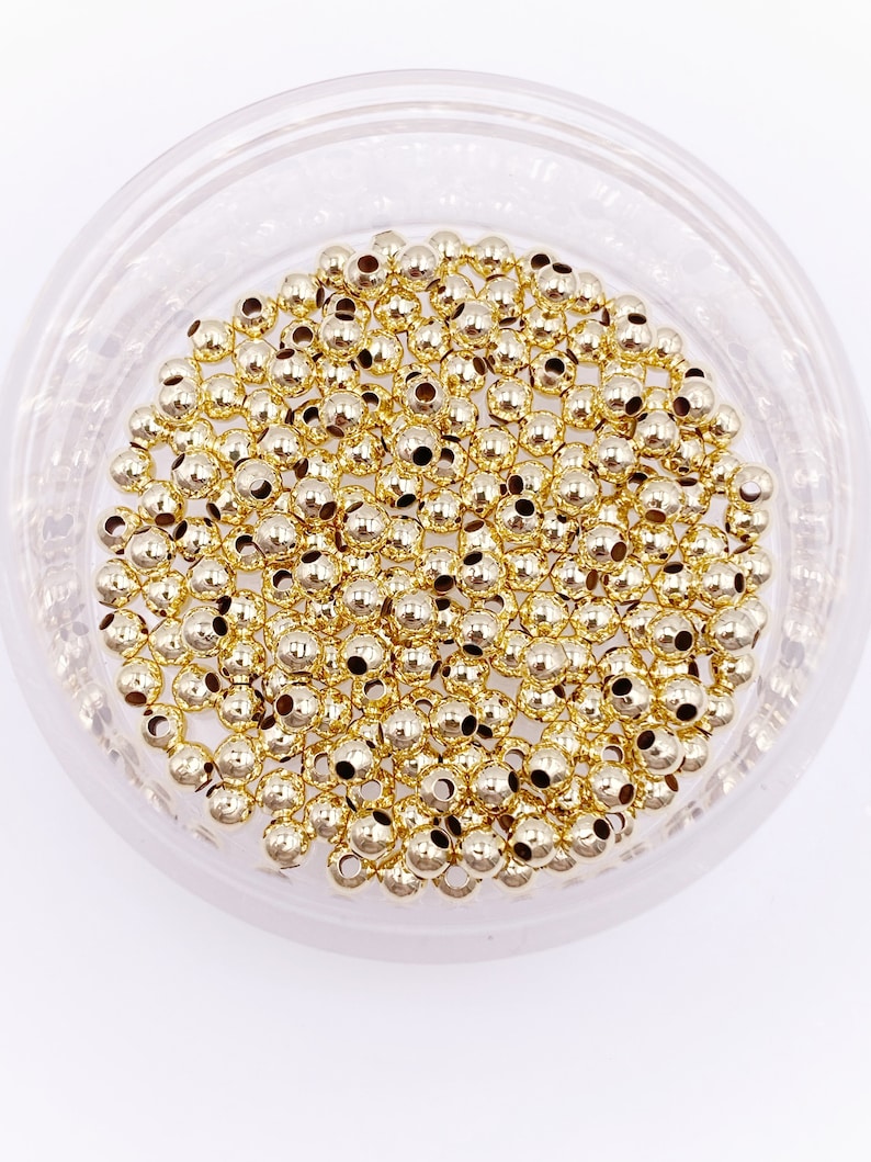 K&ouml;nnte beinhalten: Eine Schale gef&uuml;llt mit goldfarbenen Metallperlen. Die Perlen sind rund und haben eine glatte, gl&auml;nzende Oberfl&auml;che.