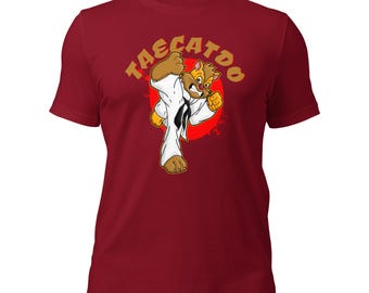 Könnte beinhalten: Rotes T-Shirt mit einer Cartoon-Illustration einer Katze, die einen Karate-Tritt ausführt. Der Text "TAE CAT DO" ist in Gelb über der Katze geschrieben.