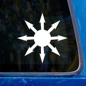 Puede incluir: Pegatina de vinilo blanco de una estrella de ocho puntas con flechas que apuntan hacia afuera. La estrella está en la ventana de un coche azul.