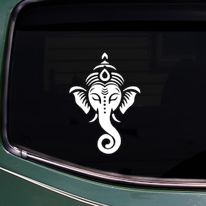 May include: White vinyl decal of the Hindu deity Ganesha, featuring a detailed design of the elephant-headed god's face. The decal is displayed on a car window, showcasing the intricate artwork.
