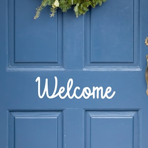 May include: A blue front door with a white "Welcome" sign and a gold door handle.