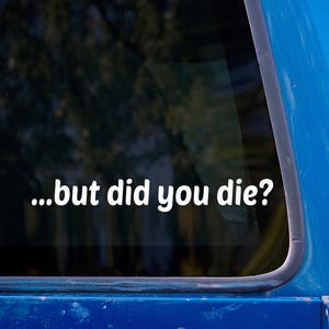 May include: White vinyl sticker with the text "...but did you die?" on a car window. The text is in a sans-serif font. The car is blue, and the background is out of focus.