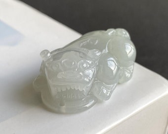 May include: A white jade carving of a mythical creature, possibly a lion or a dragon, with intricate details and a smooth, polished finish.