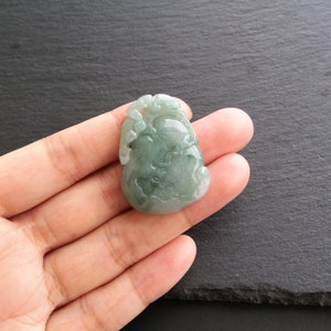 以下が含まれることがあります： 緑色の翡翠で彫られたひょうたんの形をしたペンダント。ペンダントは複雑なディテールと滑らかで磨かれた仕上げが施されています。