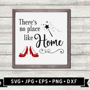 May include: A white sign with a black frame and the text "There's no place like Home" in black script font. There are red ruby slippers and a black magic wand with a star on the end. The sign is on a wood background.