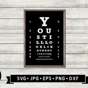 May include: A framed black and white print with an eye chart design. The chart features the phrase "YOU STILL LOOK" in large white letters. The print is on a white wooden background. The bottom of the image has the text "SVG • JPG • EPS • PNG • DXF".