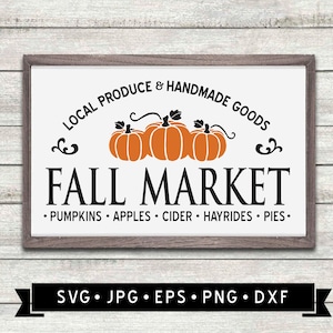 May include: A white sign with a brown frame, advertising a Fall Market with local produce and handmade goods. The sign features three orange pumpkins with black stems and leaves. The text reads "LOCAL PRODUCE & HANDMADE GOODS FALL MARKET • PUMPKINS • APPLES • CIDER • HAYRIDES • PIES •"
