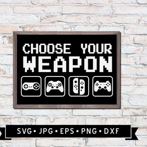 May include: A black framed sign with white text that reads "Choose Your Weapon" with pixelated font. The sign has four icons of different video game controllers: a Super Nintendo controller, a Playstation controller, a Nintendo Switch controller, and an Xbox controller.