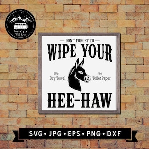 May include: A framed sign with the text "DON'T FORGET TO - WIPE YOUR" above a black donkey illustration. Below the donkey are the words "HEE-HAW". The sign also includes the text "15¢ Dry Towel" and "5¢ Toilet Paper".