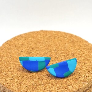 May include: A pair of blue, green, and turquoise half-circle earrings made of polymer clay.