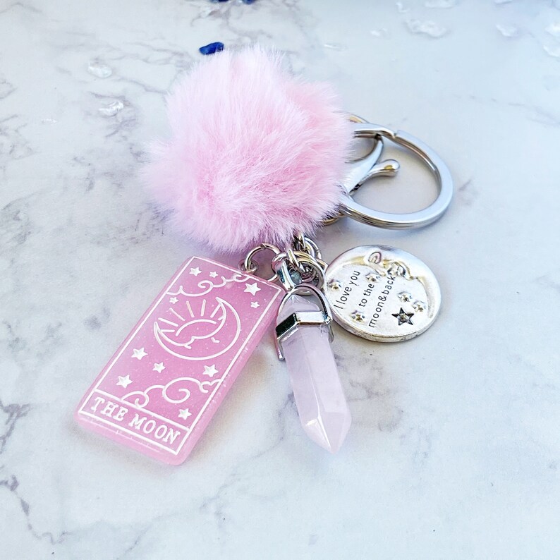Peut inclure: Porte-cl&eacute;s en fourrure rose avec un charme de carte de tarot rose qui dit "The Moon", un charme de cristal rose et un charme argent&eacute; qui dit "I love you to the moon & back".