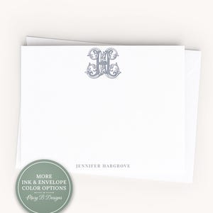 May include: A white stationery card featuring a gray ornate letter H monogram centered at the top and the name JENNIFER HARGROVE printed in gray at the bottom. A circular green badge in the corner displays the text MORE INK & ENVELOPE COLOR OPTIONS.