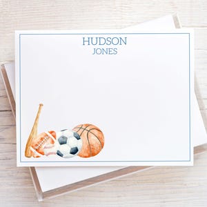 May include: White stationery with a blue border and the name "HUDSON JONES" printed at the top. Watercolor illustrations of a baseball bat, football, soccer ball, and basketball are featured on the bottom left.