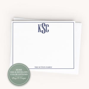 May include: A white rectangular stationery card with a dark blue border, featuring a centered dark blue monogram with the letters KSC and the text THE SUTTON FAMILY at the bottom. A circular sage green badge displays the text MORE INK & ENVELOPE COLOR OPTIONS and Mary B Designs.