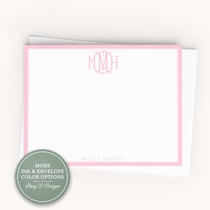 May include: A white rectangular note card with a pink border, featuring a pink monogram with the letters MMH at the top center and the name MOLLY MARTIN printed in pink at the bottom. The card is placed on top of a white envelope.