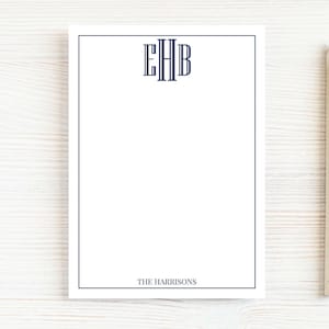 May include: White notepad with a navy blue border and monogram. The notepad features the initials "EHB" at the top and the name "THE HARRISONS" at the bottom. A pencil rests on the right side of the notepad.