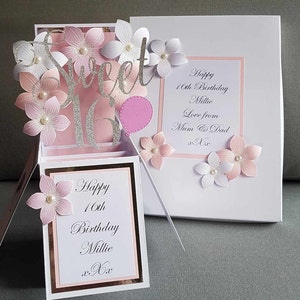 May include: A pink and white pop-up card with a silver glitter "Sweet 16" design. The card has a pink balloon and flowers. The card reads "Happy 16th Birthday Millie Love from Mum & Dad xxx".