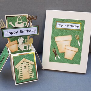 Op de afbeelding: Een groene en gouden pop-upkaart met een tuinmotief. De kaart toont een klein schuurtje, tuingereedschap en de tekst "Happy Birthday".