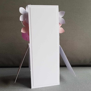 May include: A white card with a blank front and a decorative floral design on the back. The flowers are pink, purple, and white.