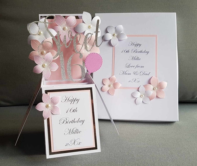 May include: A pink and white pop-up card with a silver glitter 'Sweet 16' design. The card has a pink balloon and flowers. The inside of the card says 'Happy 16th Birthday Millie xx'.