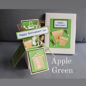 Op de afbeelding: Een groene en witte pop-upkaart met een tuinmotief. De kaart is open en toont een klein schuurtje, tuingereedschap en een bord met de tekst "Happy Retirement Ian". De kaart is versierd met een groen-wit ruitpatroon. De kaart is gesloten en toont een groen-wit ruitpatroon met de tekst "Happy Retirement" in een wit rechthoek. De kaart is gelabeld "Apple Green".