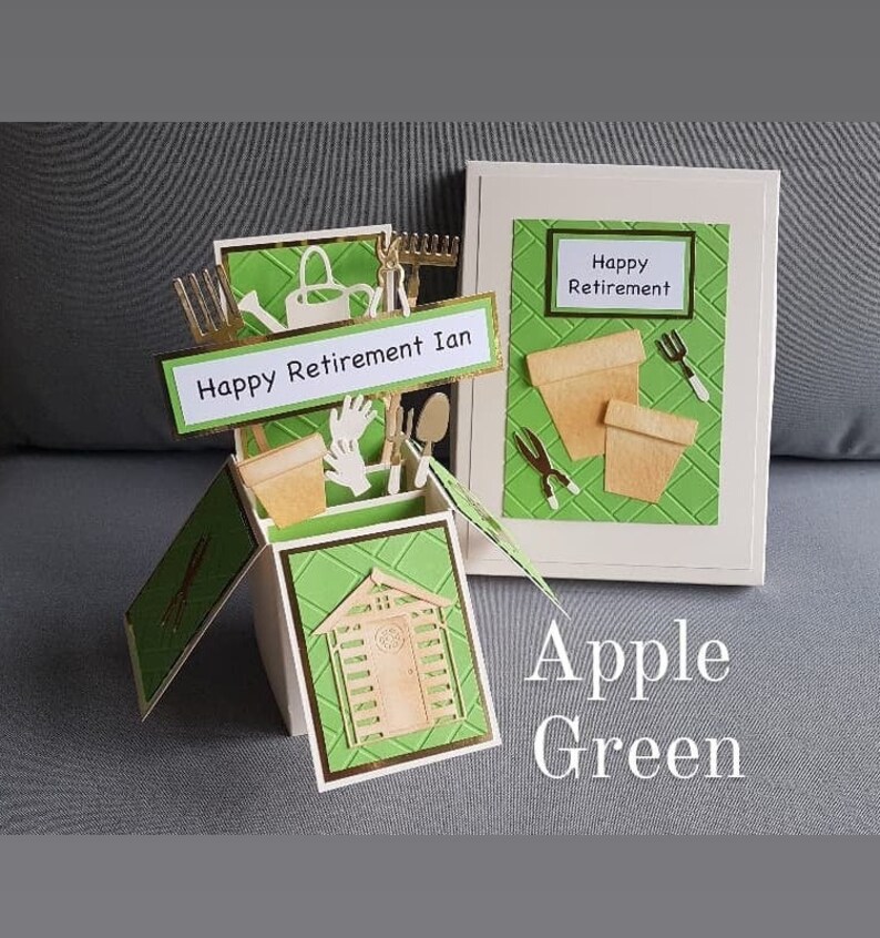 Op de afbeelding: Een groene en witte pop-upkaart met een tuinmotief. De kaart is open en toont een klein schuurtje, tuingereedschap en een bord met de tekst "Happy Retirement Ian". De kaart is versierd met een groen-wit ruitpatroon. De kaart is gesloten en toont een groen-wit ruitpatroon met de tekst "Happy Retirement" in een wit rechthoek. De kaart is gelabeld "Apple Green".
