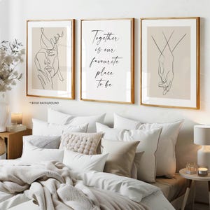 May include: A set of three framed wall art prints with gold frames. The left print shows a black line drawing of a face on a beige background. The centre print features the black text Together is our favourite place to be. The right print displays a black line drawing of two hands holding on a beige background.