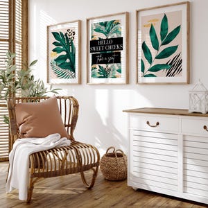 a cozy living room with a wicker chair, a woven basket, and three framed prints on the wall. The prints include tropical leaves and the text "Hello Sweet Cheeks Take a seat".