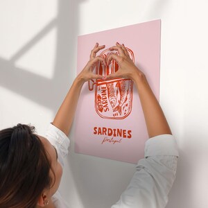 A person is holding up a poster with the word "Sardines" written on it.
