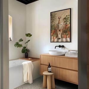 a modern bathroom with a wooden vanity, a white sink, and a framed artwork of a giraffe reading a newspaper. The bathroom is decorated with potted plants and has a minimalist design.