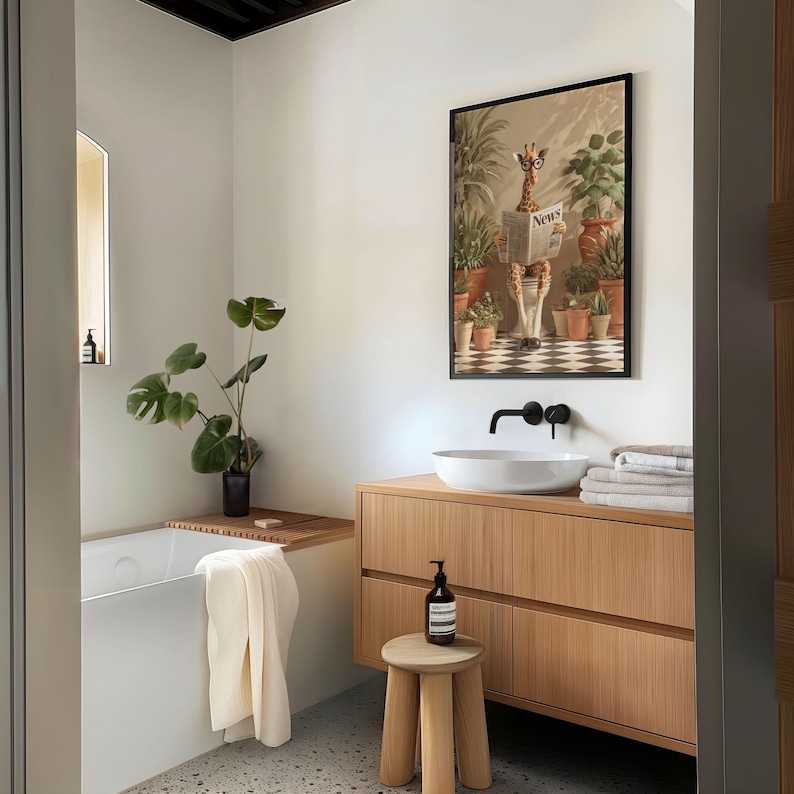 a modern bathroom with a wooden vanity, a white sink, and a framed artwork of a giraffe reading a newspaper. The bathroom is decorated with potted plants and has a minimalist design.