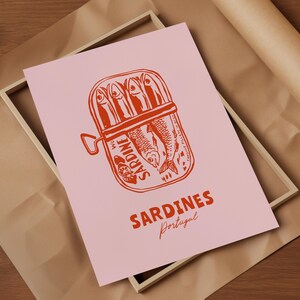 a pink poster with a red illustration of a can of sardines and the text "Sardines" written below it.