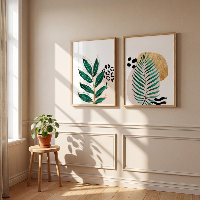 May include: Two framed botanical art prints. One features a green leaf design with gold accents and a leopard print pattern. The other print has a green palm leaf, gold circle, and abstract black shapes. Both are in light wood frames.