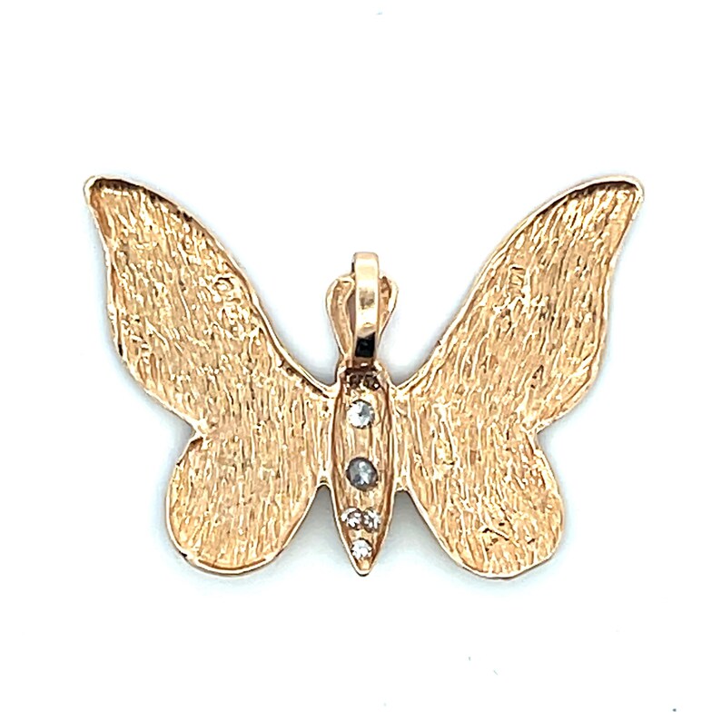 May include: A gold-coloured butterfly pendant with textured wings and three small, clear gemstones on the body. The pendant has a loop at the top for a chain. The butterfly design is symmetrical.