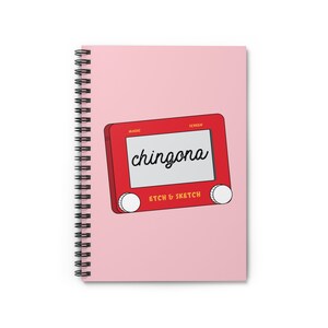 Op de afbeelding: Een roze notitieboek met een rode Etch A Sketch tekening van het woord "chingona" op het scherm.