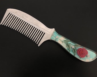 Vintage handmade hair comb with floral pattern on the handle.