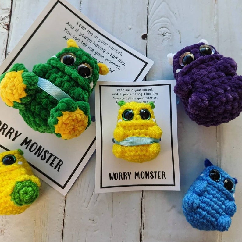 Puede incluir: Cuatro monstruos de la preocupaci&oacute;n hechos a crochet, cada uno de un color diferente y con una m&aacute;scara facial. El texto en la tarjeta dice "Gu&aacute;rdame en tu bolsillo. Y si est&aacute;s teniendo un mal d&iacute;a. Puedes contarme tus preocupaciones. Monstruo de la preocupaci&oacute;n."