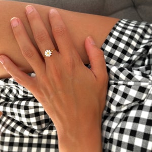 May include: A gold ring with a white daisy flower design.