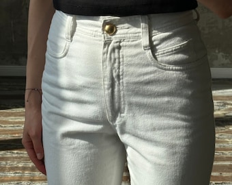 May include: White high-waisted jeans with a gold button closure.